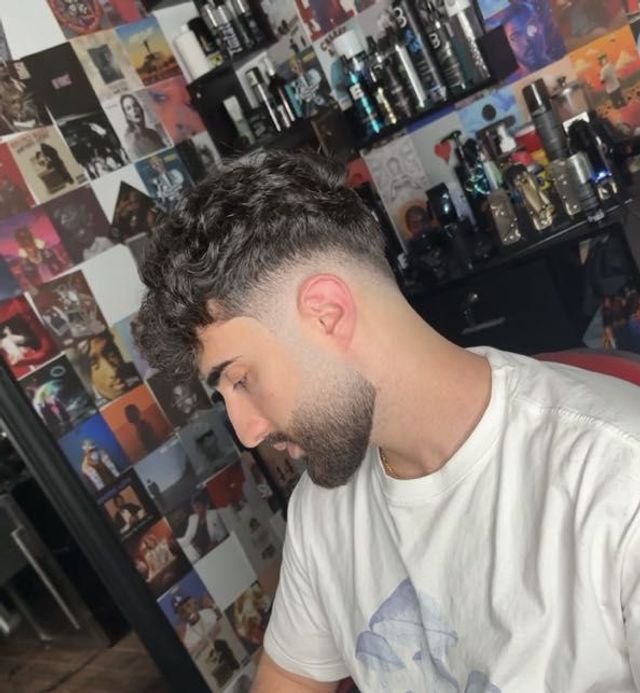 Curly top with a precise fade and beard
